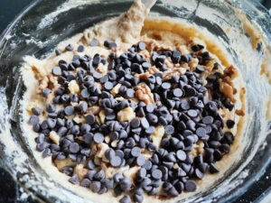 Adding Roasted Walnuts and Chocolate Chips into cake batter in a bowl