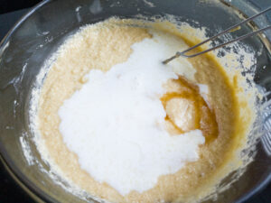 Adding Yoghurt + Milk mixture and vanilla extract into cake batter in a bowl