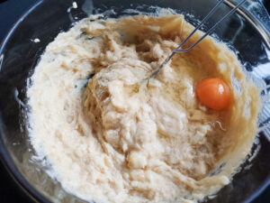 Adding eggs (one by one) into the cake batter in a bowl