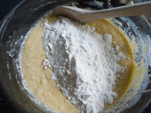 Adding flour mixture into the cake batter in a bowl