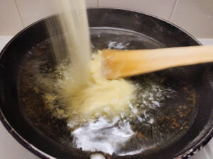 Adding roasted semolina to boiled water in a pan