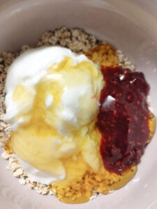 Adding yoghurt, confiture or jam and honey in the rolled oats and chia seeds mixture in a cereal bowl