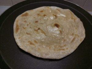 Cooked chapati with ghee on a pan