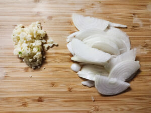 Minced garlic and sliced onions on a cutting board