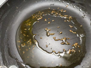 Sauteeing jeera in ghee in a pan