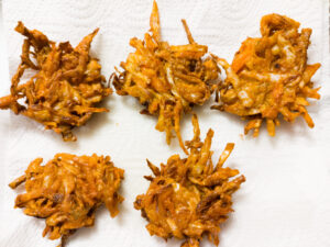 Vegetable pakora cooling on a plate laced with dry kitchen paper