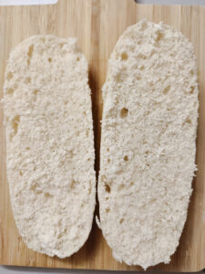 Equally halved mini baguette on a cutting board 