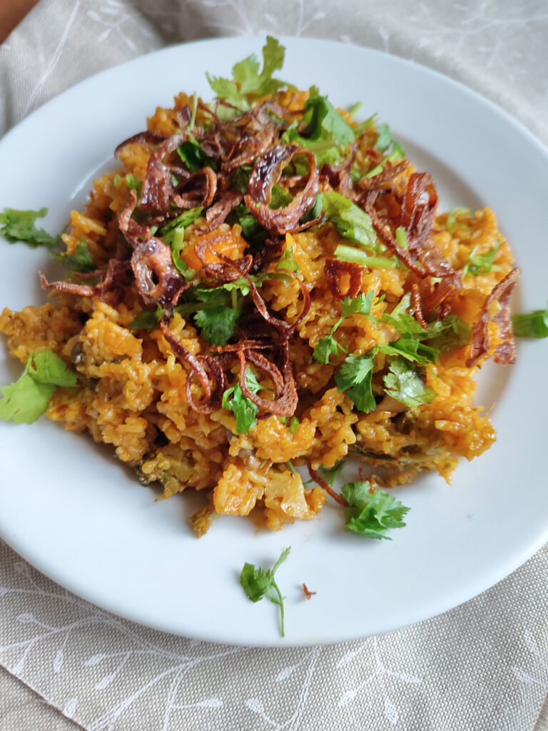 Vegetable Biryani served on a white plate placed on a decorative cloth