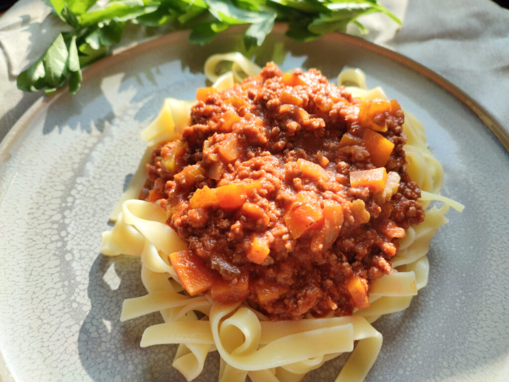 Ragù alla Bolognese on a grey plate with leaves as side decoration