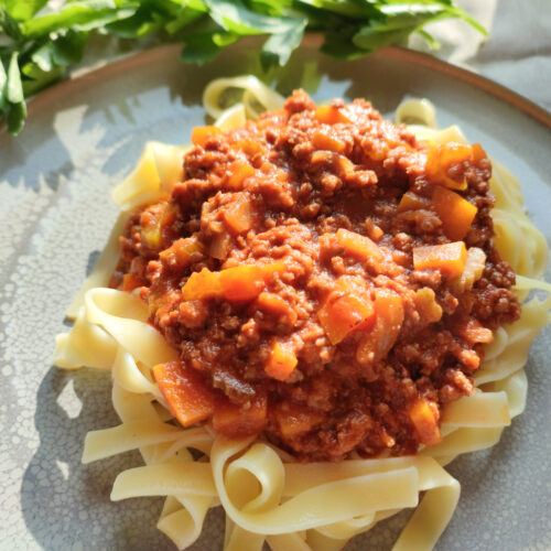 Ragù alla Bolognese on a grey plate with leaves as side decoration