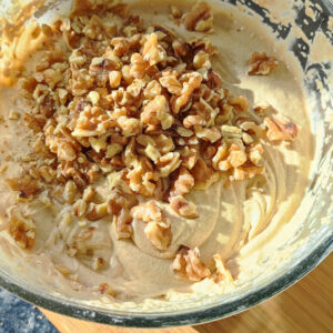 Adding in walnuts into the cake batter in a bowl