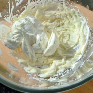 Adding mascarpone cream to the whipped cream in the bowl