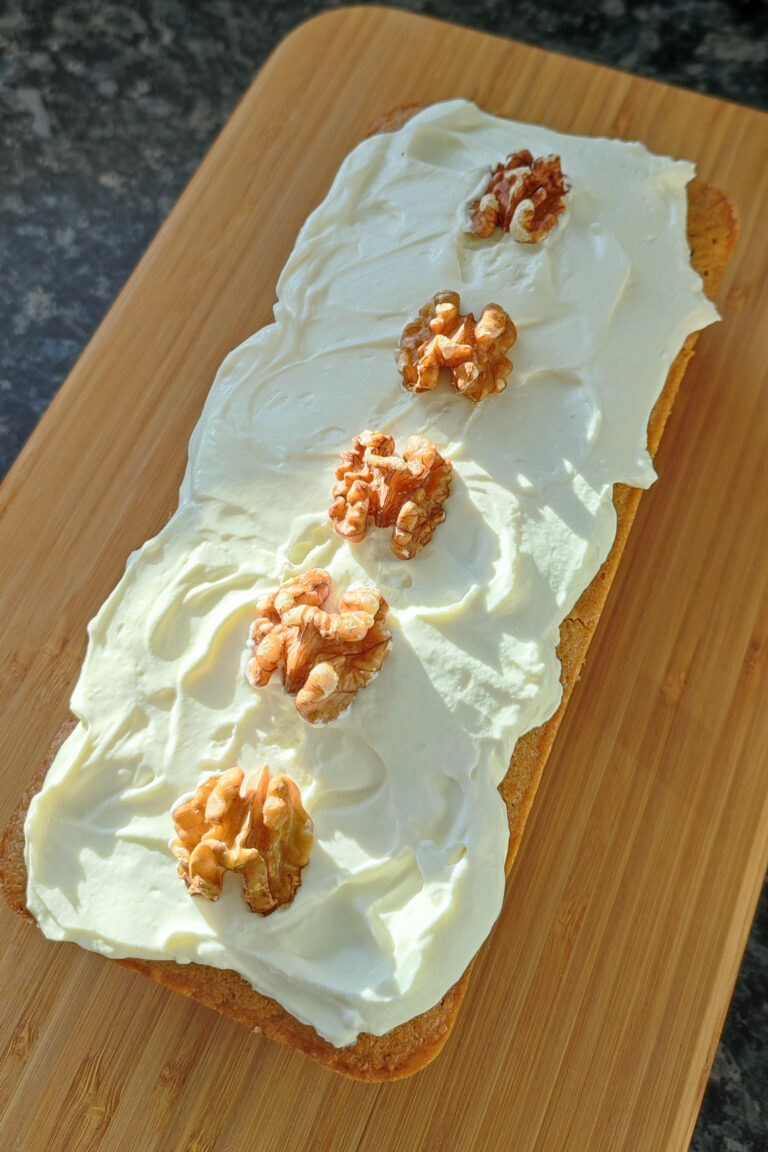 Coffee Walnut Mascorpone cake with Mascorpone Whipped Cream frosted and decorated with walnuts on a wood surface with blue medley background