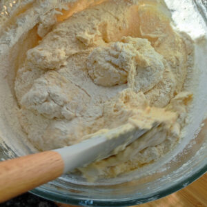 Folding in one of third self rising flour into the cake batter using a spatula in a bowl