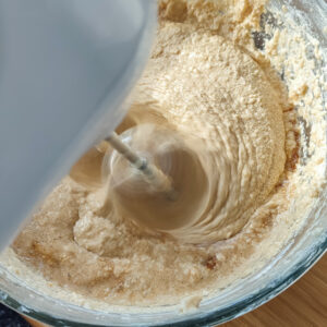 Incorporating three of third coffee into the cake batter in a bowl using a hand mixer