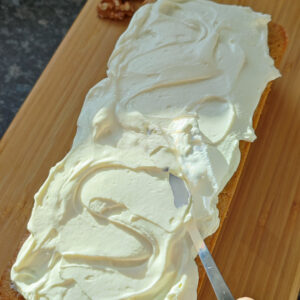 Spreading mascarpone whipped cream on the cooled cake using a frosting spatula