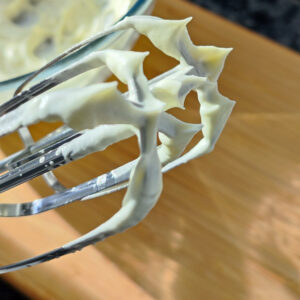 Stiff peaks from whipped cream on the hand mixer whisk