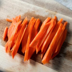 Carrots cut into matchsticks on a cutting board