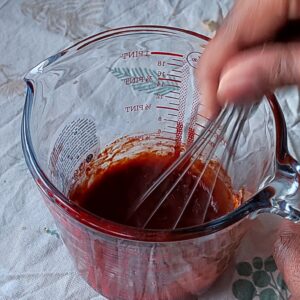 Whisking Gochujang sauce mix ingredients in a mixing bowl with a whisk