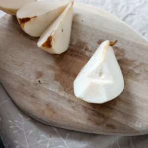 A piece of cored pear on a chopping board