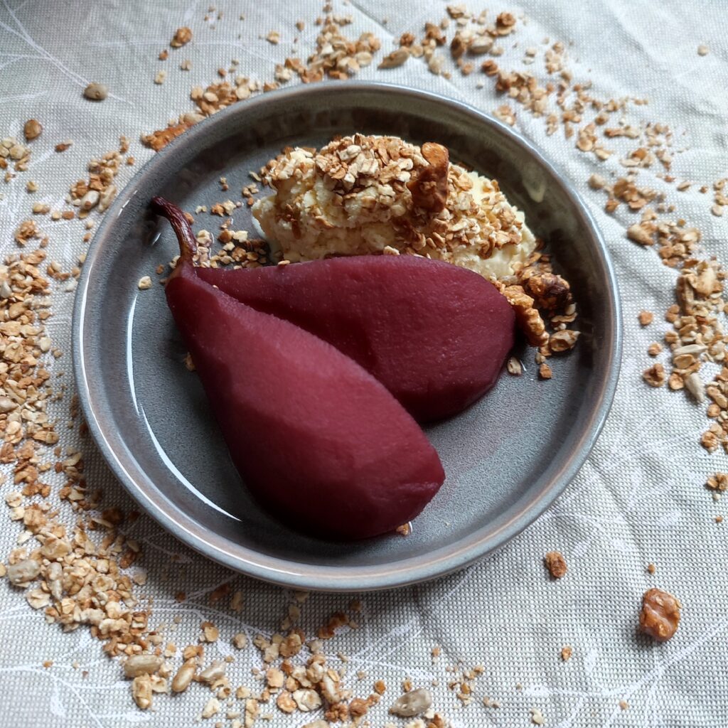 Stoofpeertjes b-roll 1 : Two pieces of pear with a scoop of ice cream and a sprinkle of granola on a dessert plate surrounded by a ring of granola trail