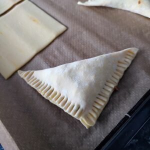 Crimped Cheesy Keema Puff before baking on a lined baking tray