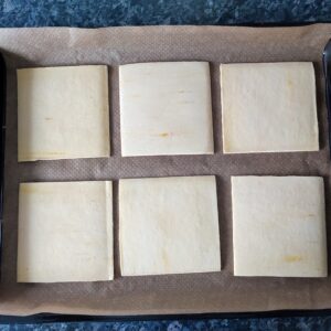 Line puff pastries square sheets on a lined baking tray