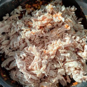 Adding shredded chicken on a pan