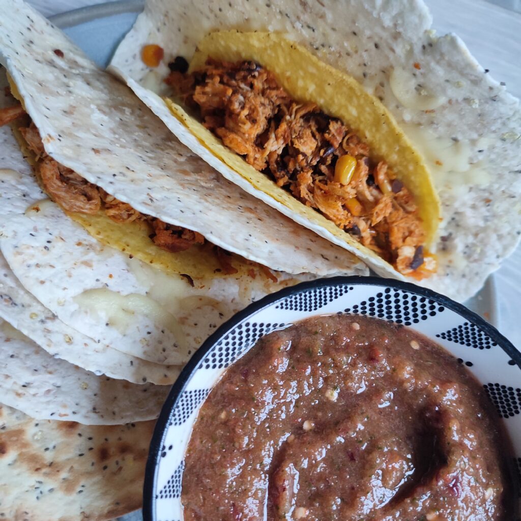 B roll 2 Crunchy Chicken Tacos on a grey plate with a side of pureed pico de gallo in a black and white patterned bowl