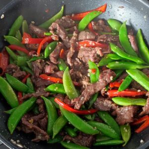 Stir fried sugar snap peas, thinly sliced bell peppers, minced garlic and minced ginger in a wok