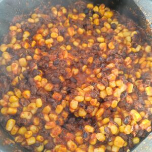 Stir frying black beans , canned corn and taco seasoning on a pan