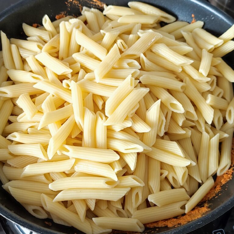 Adding cooked penne in the pan on the stove