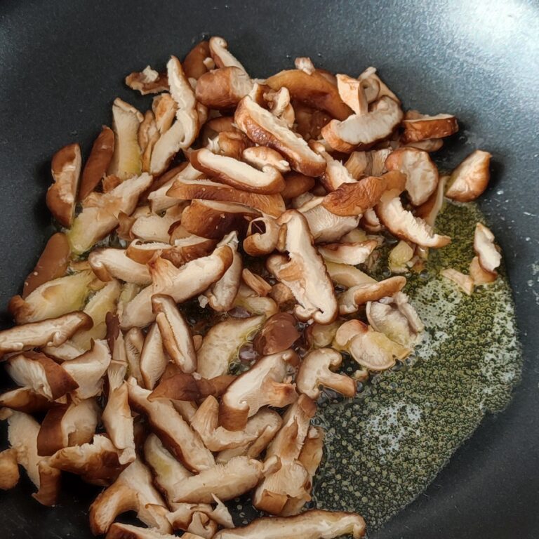 Adding shiitake mushrooms slices in the pan