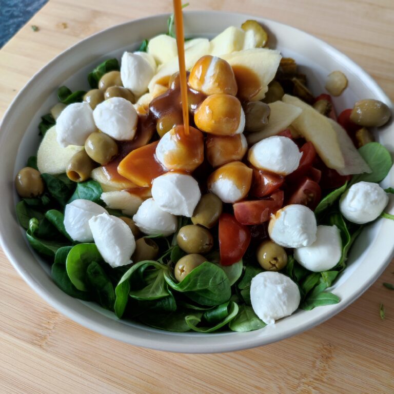 Adding the vinaigrette to the salad in a large bowl on the working surface