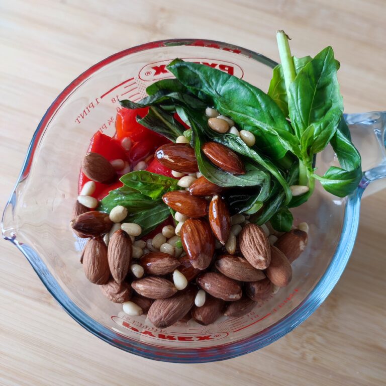 Red Pesto ingredients before blending in a mixing glass jug on the wood surface