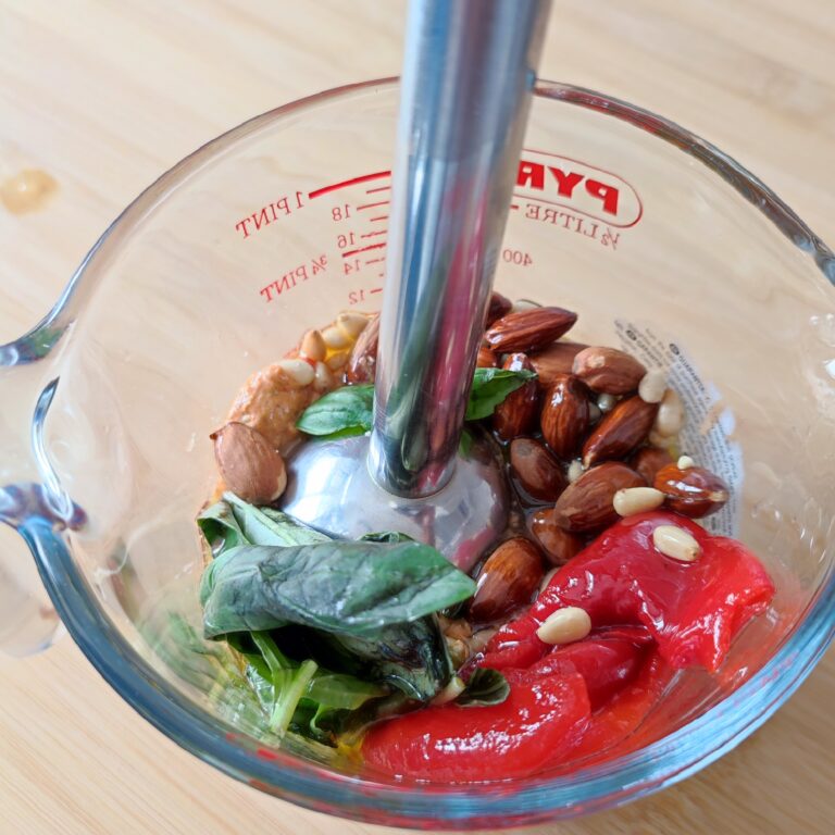 Red Pesto ingredients during the blending process in a glass mixing jug