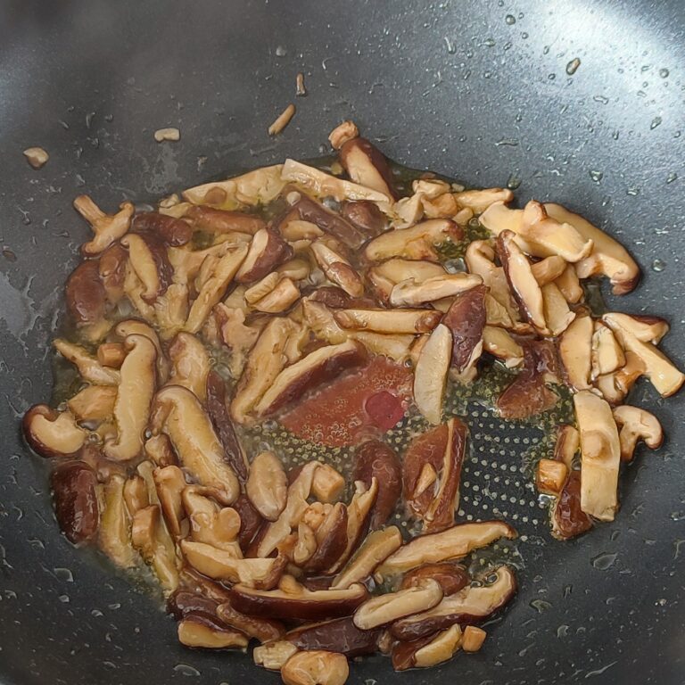 Stir fried shiitake mushrooms slices in the pan on the stove