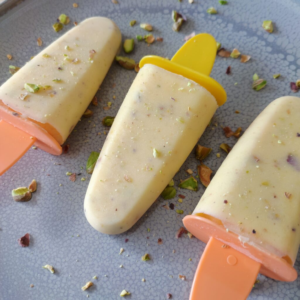 B roll 1 Mango Cardamom Pistachio Popsicles topped with roasted pistachios on large gray plate