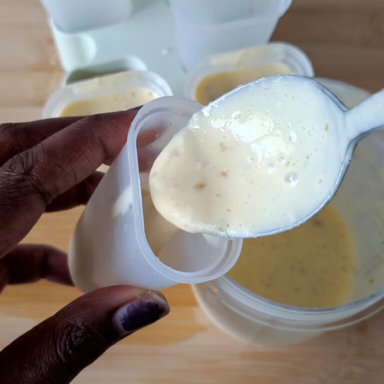 Filling the a popsicle mould with the blended ingredients using a spoon