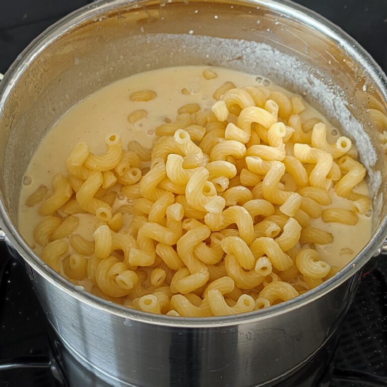 Adding the al dente celentani pasta into the cheesy creamy mixture in the pot