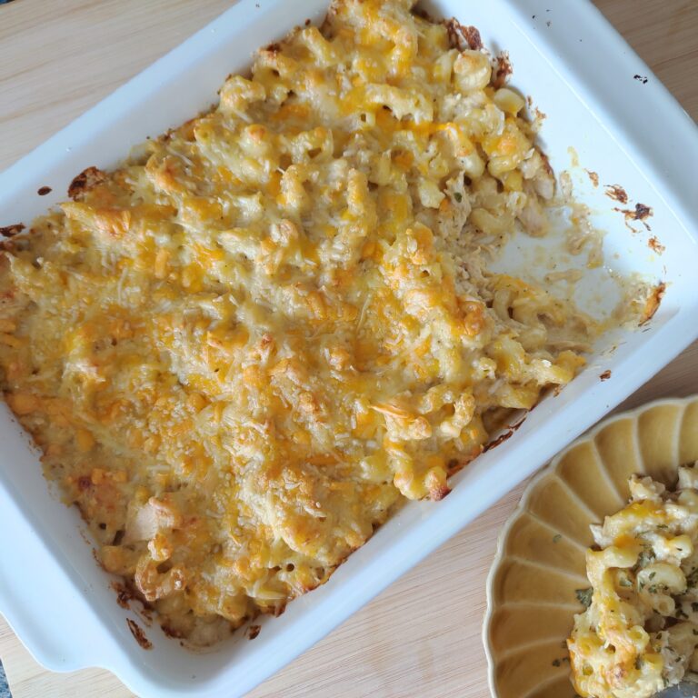 Classic Baked Mac & Cheese in a casserole dish with a chunk of it in the corner taken off