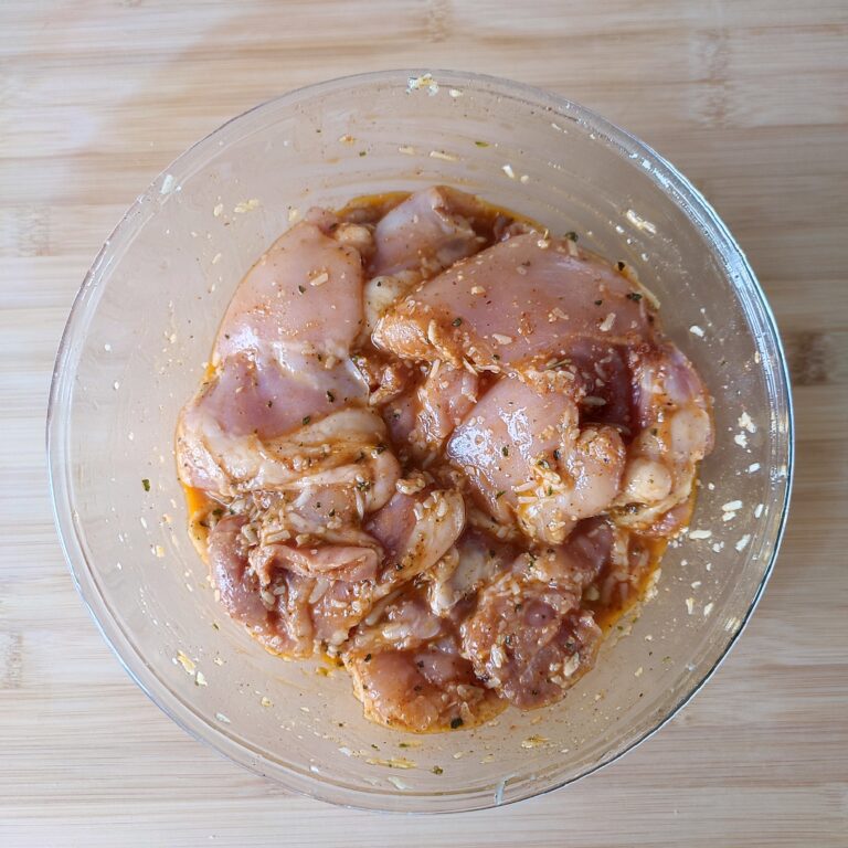 Seasoned chicken in a large bowl on a work surface