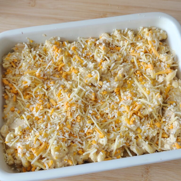 Topping the top of the mac and cheese with the reserved cheese in the casserole dish on the working surface