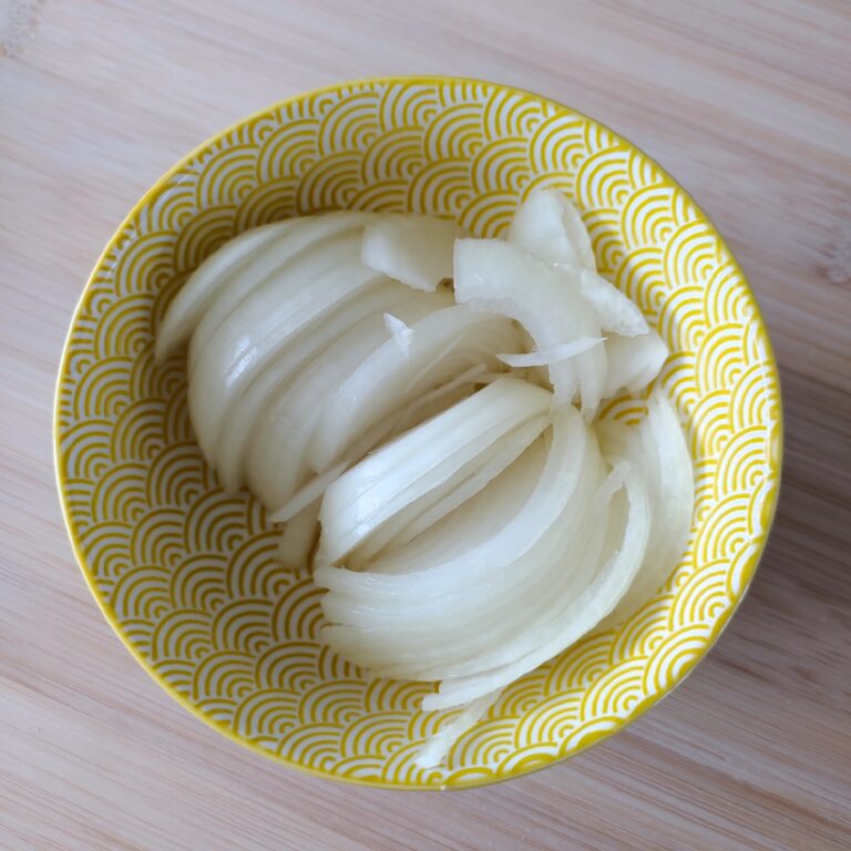 Sliced Onions in a yellow patterned bowl on a working surface