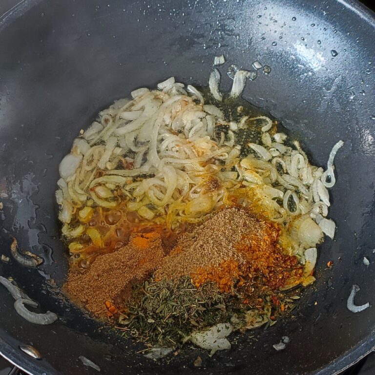 Adding spice mix to the lightly browned onions pieces in a pan