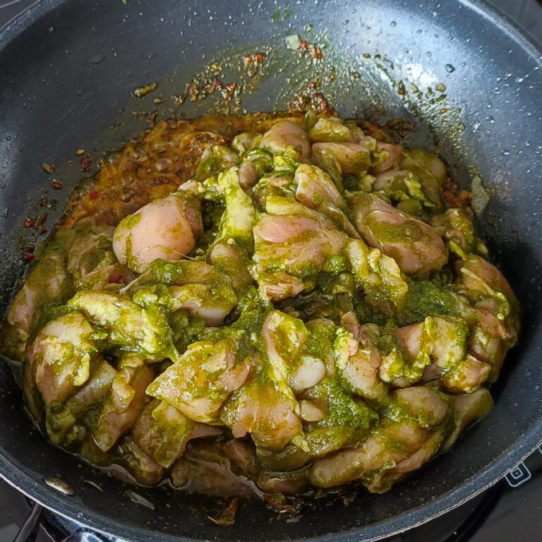 Adding marinaded chicken to the sauteed onion and spices mix in a pan