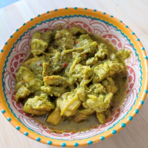 Portion of Trinidad Curry Chicken in a patterned bowl on a work surface