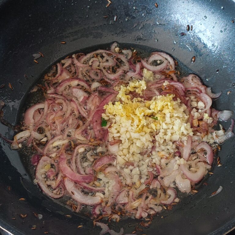 Adding minced ginger and garlic to sauté in a large pan