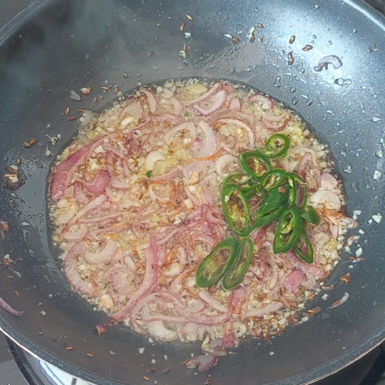 Adding sliced chillis to sauté in a large pan