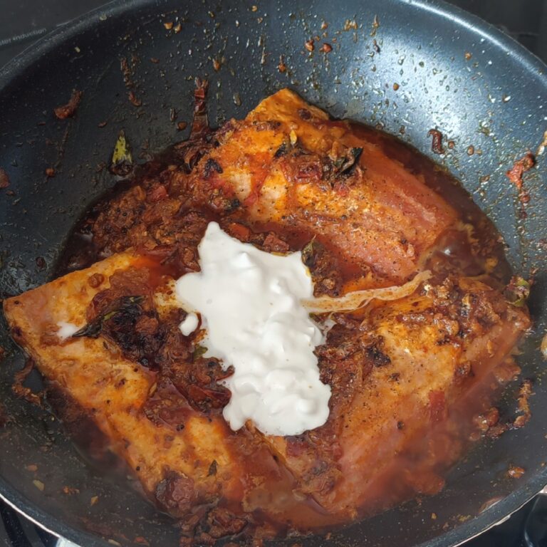 Adding coconut milk, lemon juice, salt and black pepper to fish in tomato spice mixture in a large pan